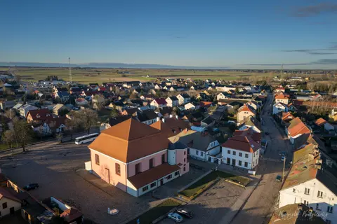 Czerwony dach zabytkowego budynku góruje nad zwartą zabudową miasteczka.