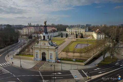 Pałacowa brama otwiera widok na dziedziniec i geometryczny ogród.