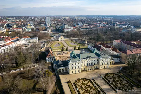 Pałac i regularne ogrody na tle rozległej miejskiej zabudowy.