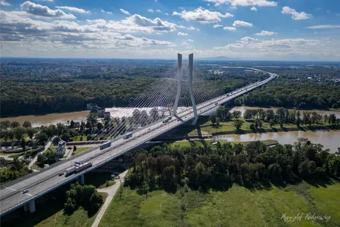 Wysokie pylony i wachlarze lin podtrzymują most rozpięty nad szeroką rzeką.