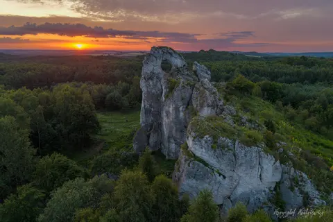 Samotna wapienna skała góruje nad lasem w pierwszym świetle poranka.