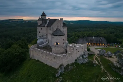 Kamienny zamek na wapiennym wzgórzu w spokojnym świetle wczesnego poranka.