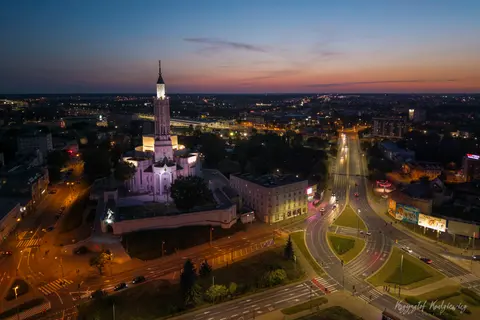 Smukła, podświetlona wieża dominuje nad skrzyżowaniem i wieczorną panoramą miasta.