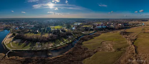Rzeka i bezlistne łąki otaczają miasteczko widoczne w szerokiej panoramie.
