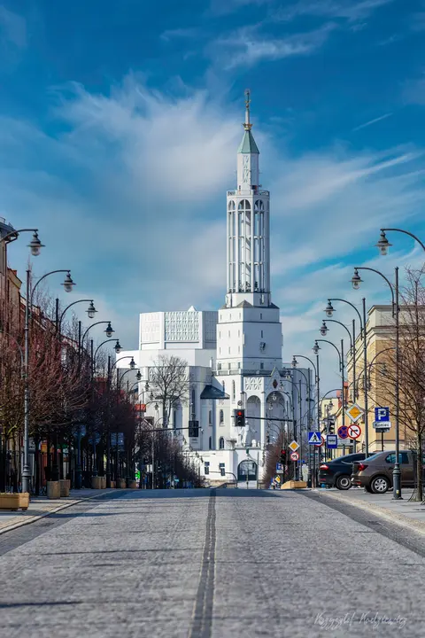 Jasna, strzelista wieża zamyka perspektywę miejskiej ulicy pod błękitnym niebem.
