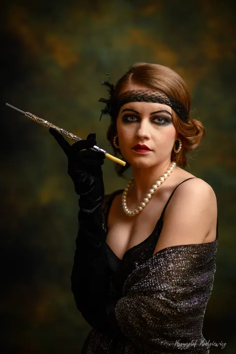 Perły, koronkowe rękawiczki i długa cygaretka w portrecie inspirowanym dawną elegancją.