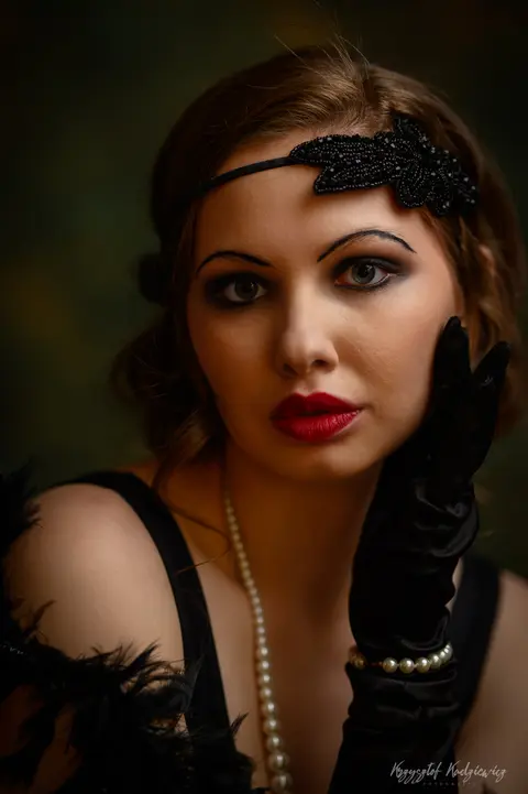 Ciasny portret kobiety w ozdobnej opasce, z wyrazistą czerwienią ust.