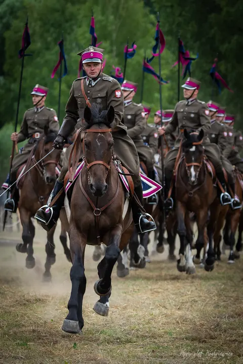 Konni jeźdźcy z lancami i barwnymi proporczykami prowadzą zwarty szyk.