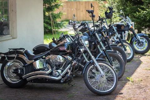 Chromowane motocykle stoją w równym rzędzie pod ścianą budynku.