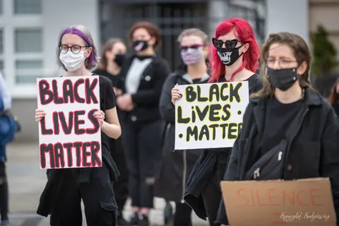 Osoby w maseczkach trzymają ręcznie wykonane tablice z napisem „Black Lives Matter”.